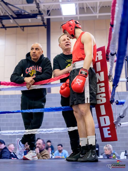 Coach Ron Pasek talks to a boxer at ringside